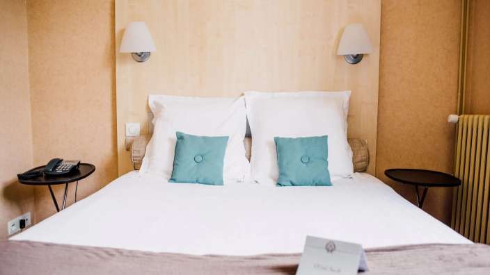 Ein Hotelzimmer mit weißem Bett und blauen Kissen