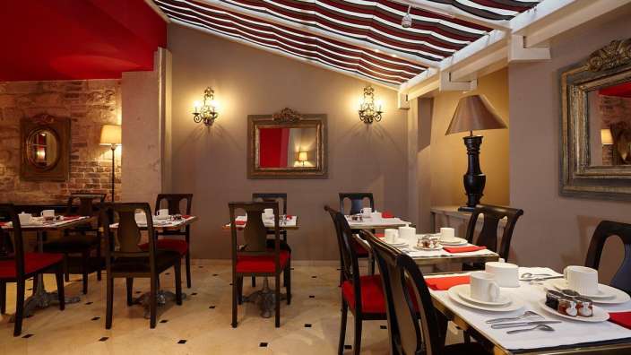 Ein Restaurant mit Tisch und Stühlen und einem gestreiften Dach