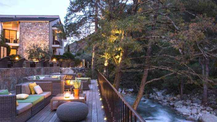 Eine Terrasse mit Möbeln und einem Fluss im Hintergrund
