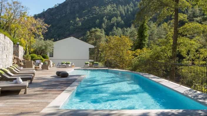 Ein großer Swimmingpool mit Liegestühlen und einem weißen Gebäude im Hintergrund