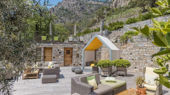 Eine Terrasse mit Möbeln und einem kleinen Häuschen mit gelbem Dach