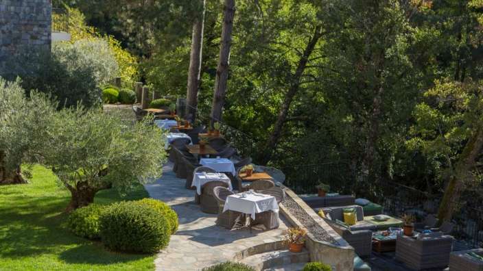 Tische und Stühle auf einer Terrasse mit Bäumen im Hintergrund
