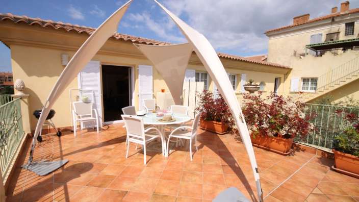 Eine Terrasse mit einem Tisch und Stühlen und einem Grill