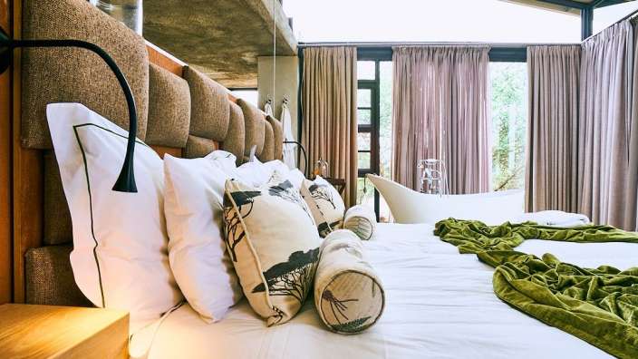 Ein Bett mit vielen Kissen und einer grünen Decke