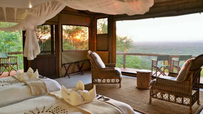 Ein Zimmer mit zwei Betten und zwei Stühlen mit Blick auf den Dschungel