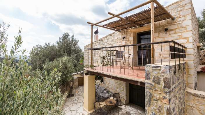 Ein Steinhaus mit einem Balkon mit Stühlen und einem Tisch