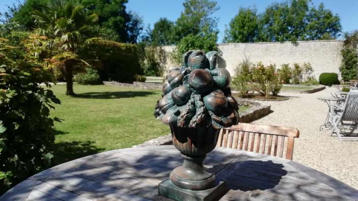 Eine Statue sitzt auf einem Holztisch in einem Garten