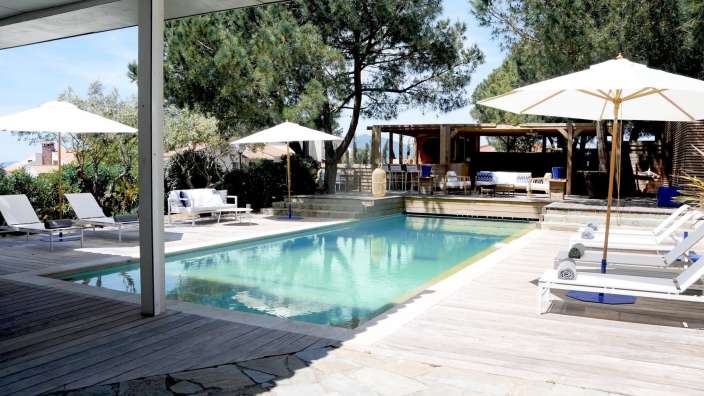 Liegestühle und Sonnenschirme umgeben einen großen Swimmingpool