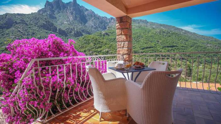 Ein Balkon mit einem Tisch und Stühlen und einem Berg im Hintergrund