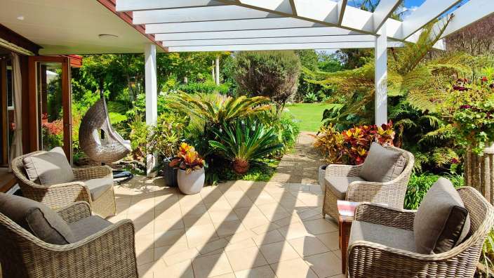 Eine Terrasse mit Stühlen und einem Tisch unter einer Pergola