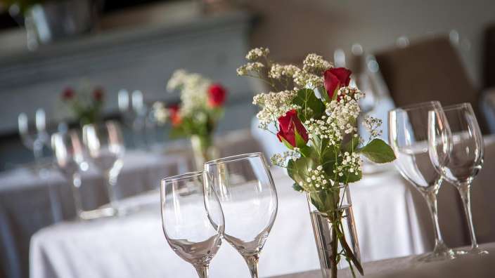 Ein Tisch mit weingläsern und einer vase mit roten rosen