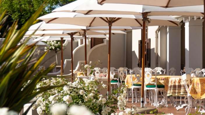 Eine Terrasse mit Tisch und Stühlen und vielen Regenschirmen