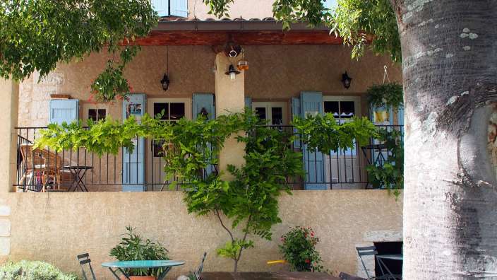 Ein Tisch und Stühle vor einem Haus mit blauen Fensterläden