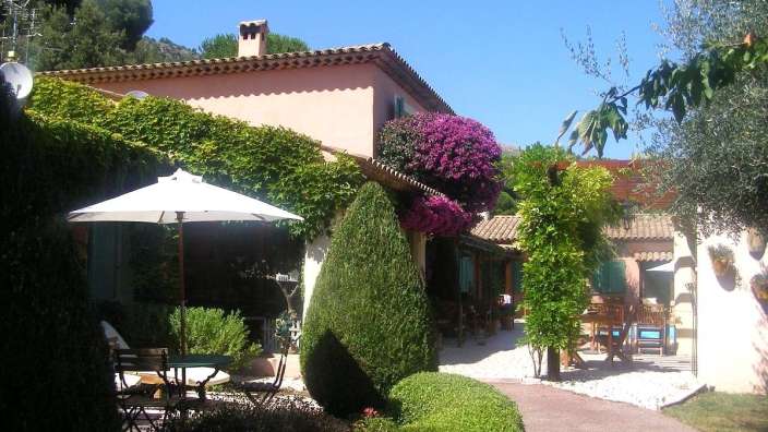 Ein großes rosa Haus mit einem Tisch und Stühlen davor