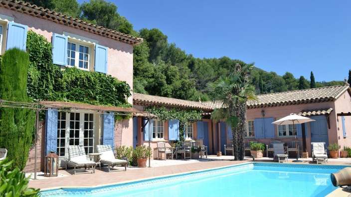 Ein großer Pool vor einem rosa Haus mit blauen Fensterläden