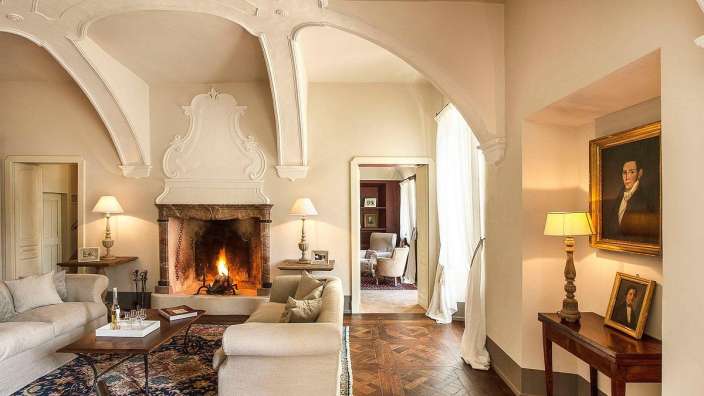 Ein Wohnzimmer mit einem Kamin und einem Gemälde eines Mannes an der Wand