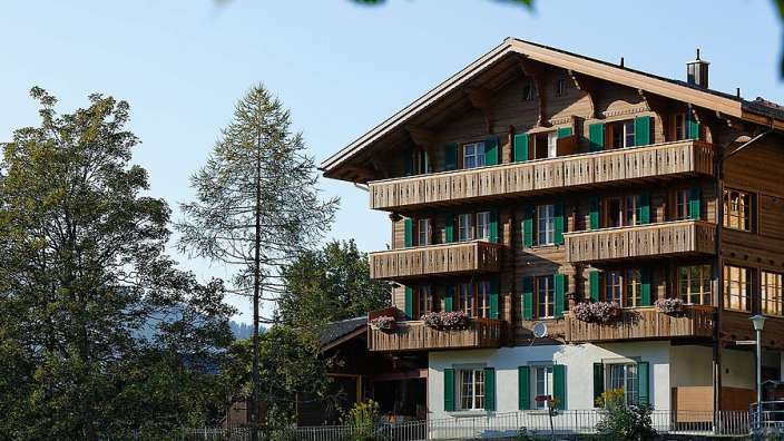 Ein großes Holzhaus mit grünen Fensterläden und Balkonen