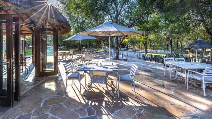 Eine Terrasse mit Tisch und Stühlen und Sonnenschirmen