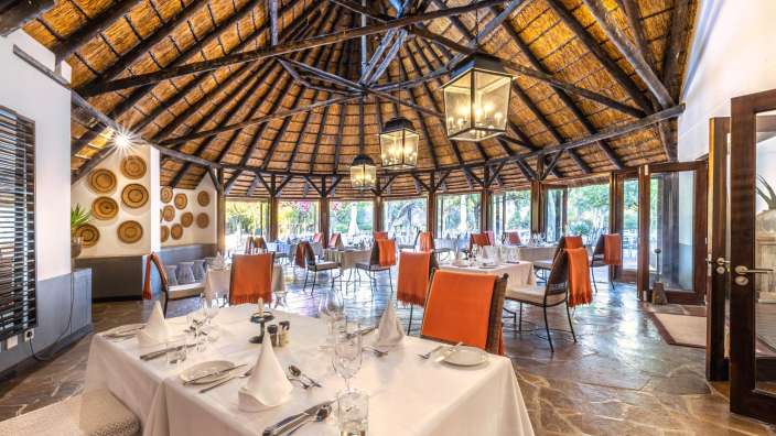 Ein Esszimmer mit Strohdach und Tisch und Stühlen