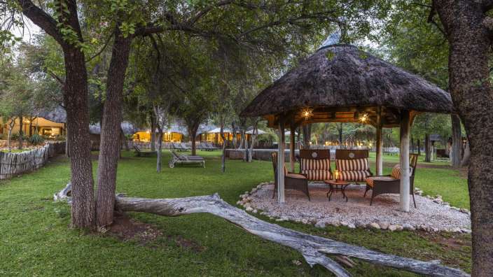 Ein Strohpavillon mit einem Tisch und Stühlen davor