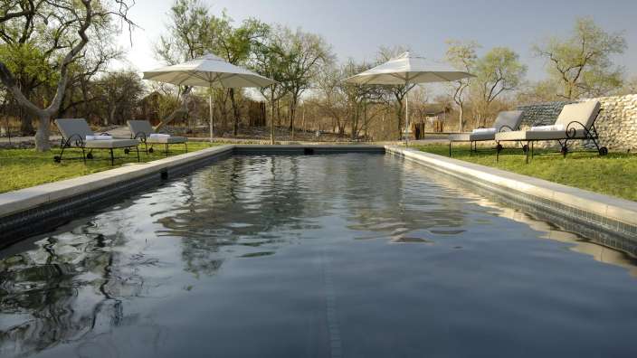 Ein Swimmingpool mit Liegestühlen und Sonnenschirmen umgeben