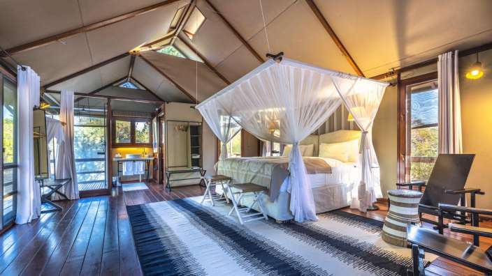 Ein Schlafzimmer mit einem Himmelbett und einem schwarz-weißen Teppich