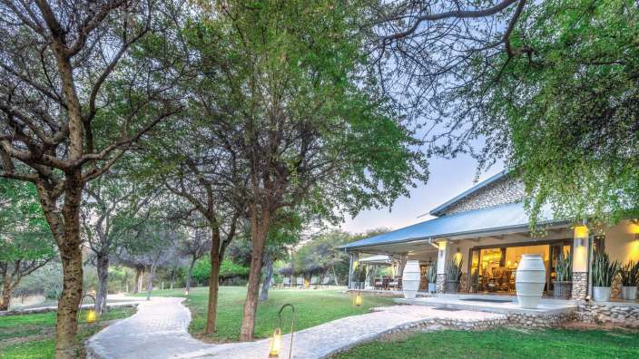 Ein weißes Haus mit einem blauen Dach und einer Veranda umgeben von Bäumen