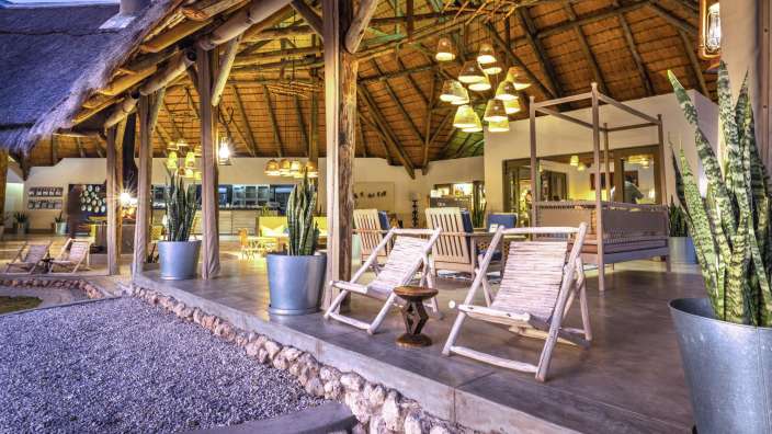 Liegestühle stehen auf einer Terrasse in einem Gebäude mit Strohdach
