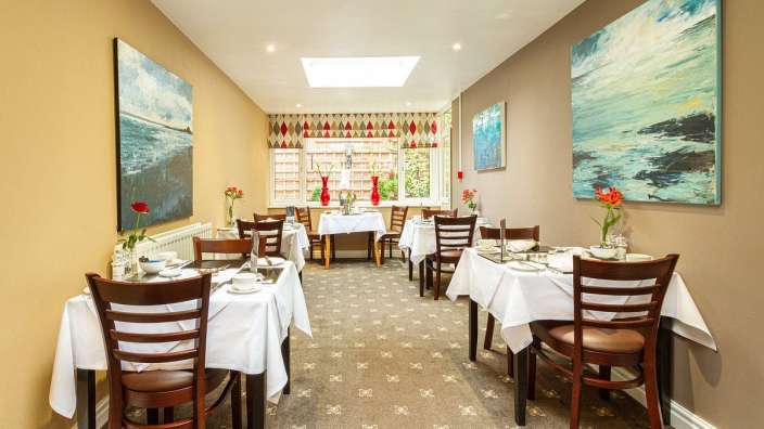 Ein Esszimmer mit Tischen und Stühlen und Gemälden an den Wänden