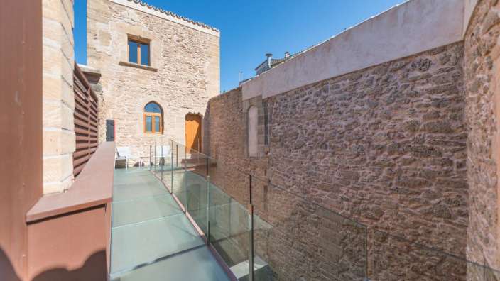Ein Balkon mit Glasgeländer zwischen zwei Steingebäuden