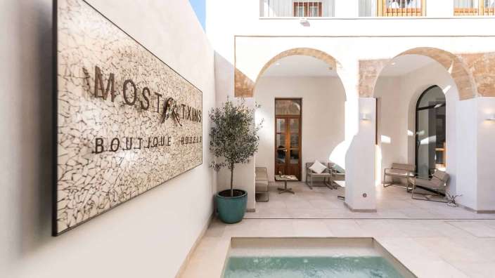 Ein weißes Gebäude mit einem Pool und einem Schild, das sagt boutique hotel