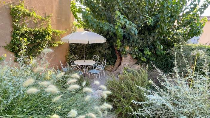Ein Garten mit einem Tisch und Stühlen und einem weißen Regenschirm