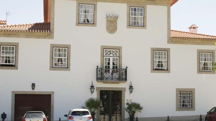 Ein weißes Gebäude mit einem Balkon und einem Wappen darauf