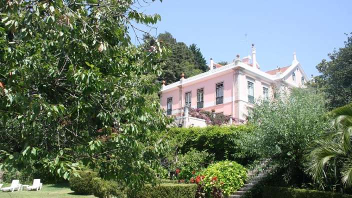 Ein großes rosa und weißes Haus steht inmitten eines grünen Gartens