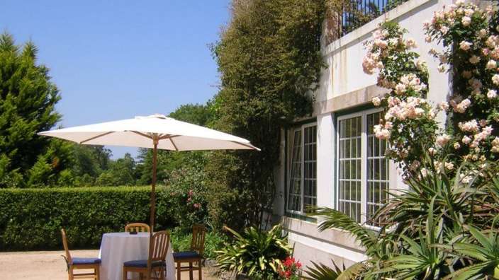 Ein Tisch und Stühle unter einem weißen Regenschirm vor einem Haus