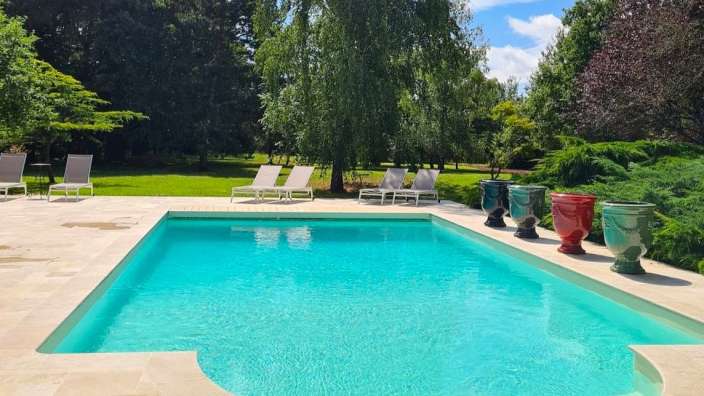 Ein großer Swimmingpool mit Liegestühlen und Vasen umgeben