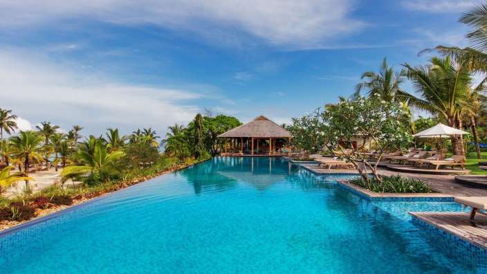 Ein riesiger Pool mit Liegestühlen und Palmen umgeben