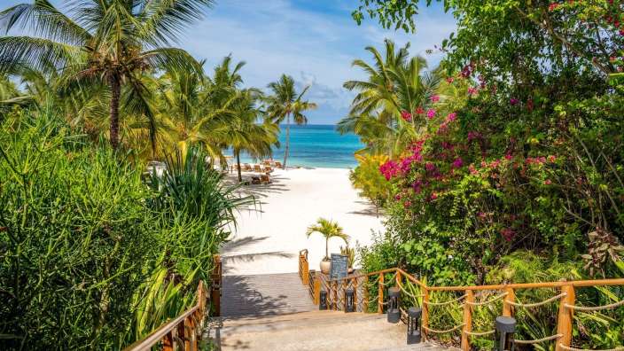 Eine Holztreppe führt zu einem weißen Sandstrand