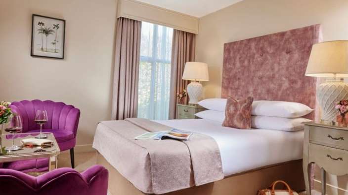 Ein Hotelzimmer mit einem Bett und einem lila Stuhl