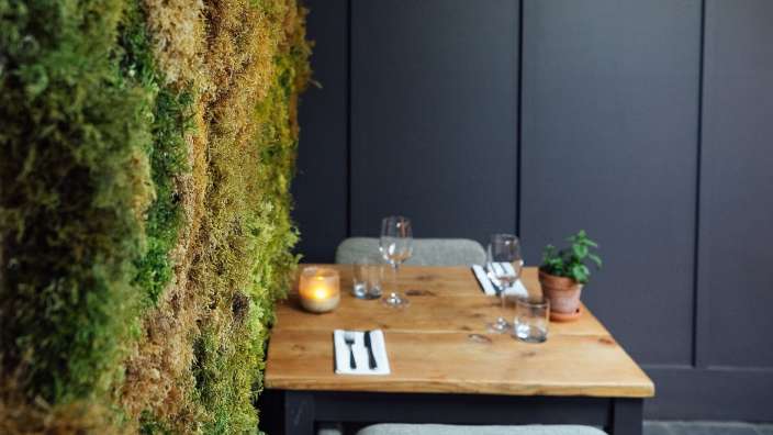 Ein Tisch mit Gläsern und Besteck vor einer grünen Wand