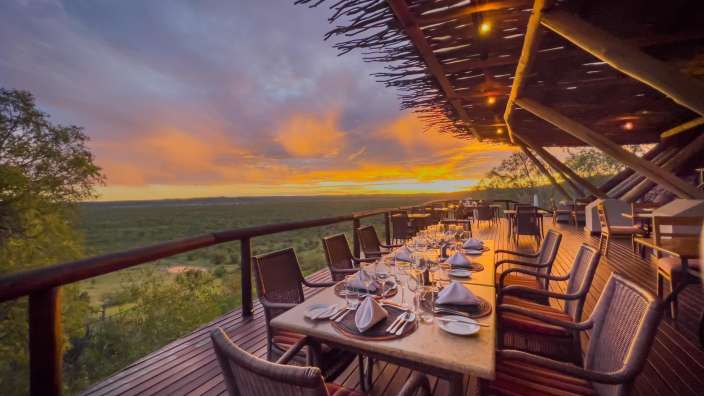 Ein Tisch und Stühle auf einem Holzdeck bei Sonnenuntergang