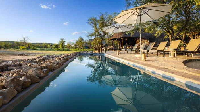 Ein Swimmingpool mit Liegestühlen und Sonnenschirmen umgeben