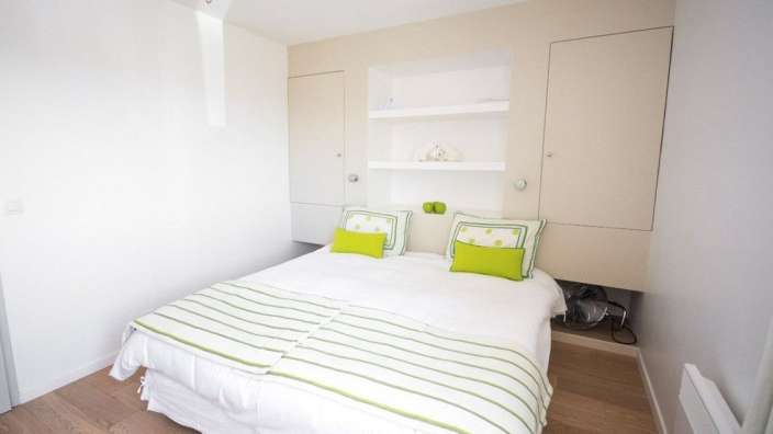 Ein Schlafzimmer mit weißem Bett und grünen Kissen