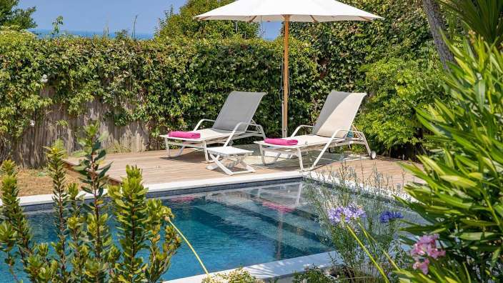 Ein Swimmingpool mit Liegestühlen und einem weißen Regenschirm