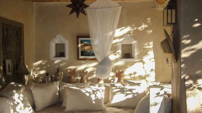 Ein Raum mit weißen Kissen und einem Himmelbett