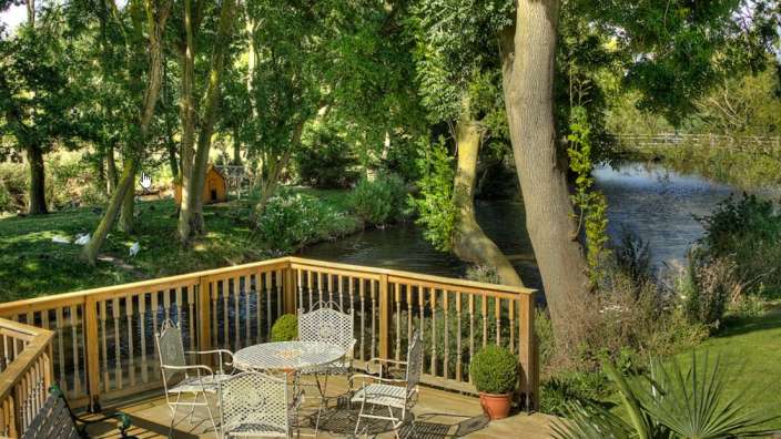 Ein Tisch und Stühle auf einem Deck mit Blick auf einen Fluss