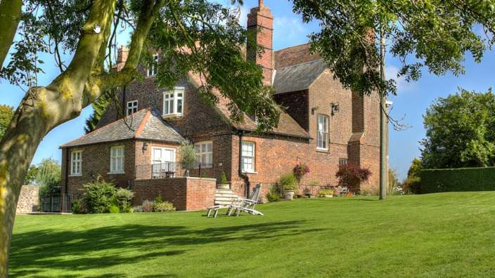 Ein großes Backsteinhaus mit einem großen Rasen davor