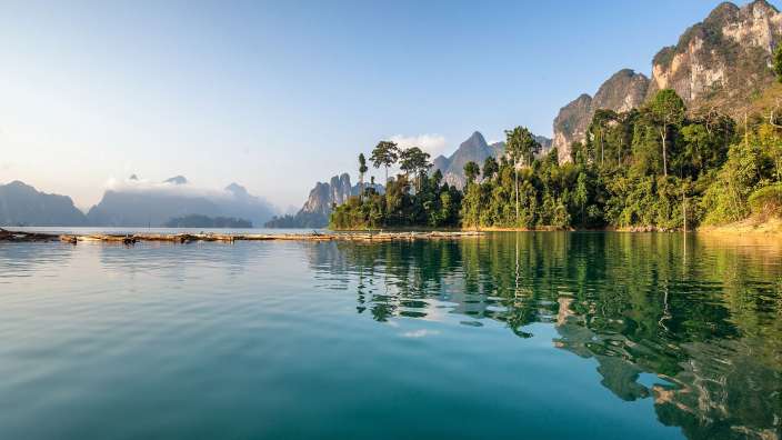 Ein See mit Bäumen und Bergen im Hintergrund
