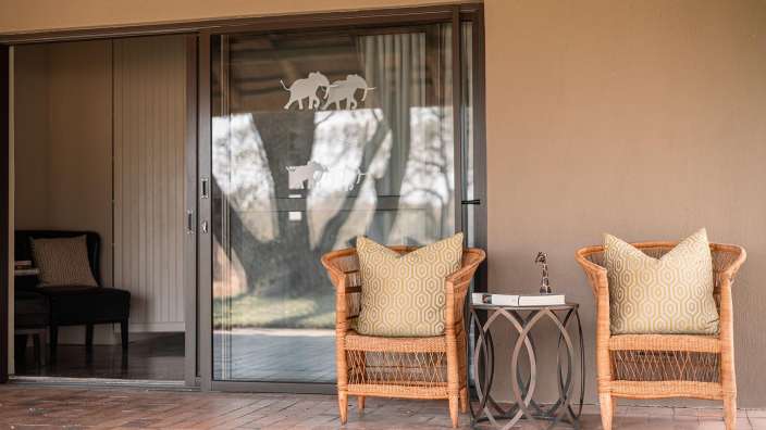 Zwei Stühle mit gelben Kissen stehen vor einer Glastür