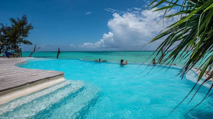 Menschen schwimmen in einem Pool mit Blick auf das Meer